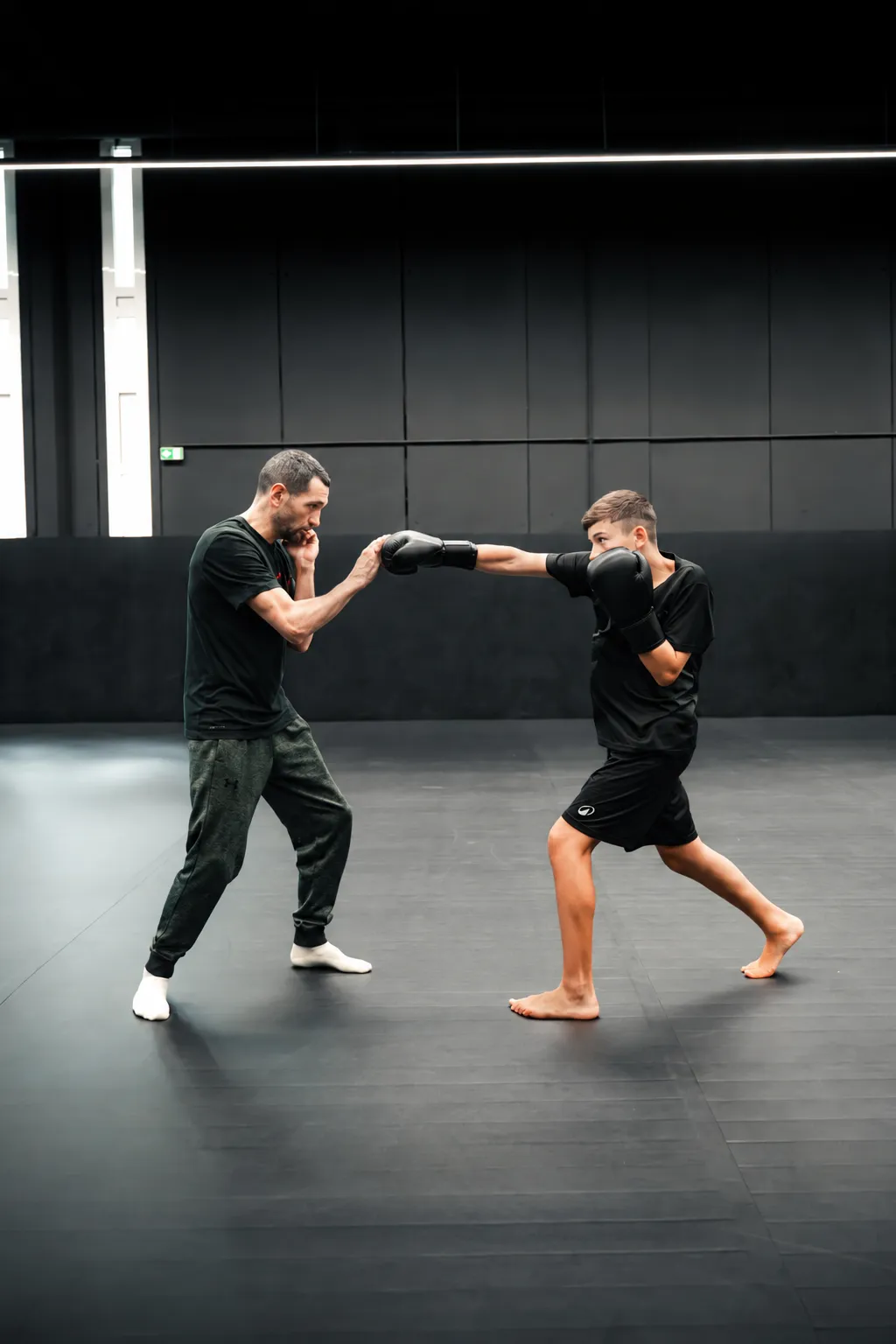 Un jeune pratiquant apprend une technique avec son coach sur les tatamis